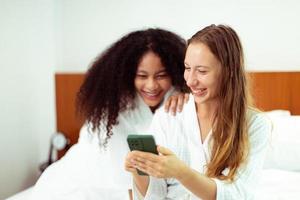 caucasico e nero donne amore insieme e abbraccio hold come diversità persona. giovane adulto romantico coppia Guarda a inteligente Telefono foto Chiacchierare testo come sensazione contento Sorridi solidarieta e diversità, copia spazio