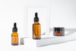 siero viso antietà al collagene in flacone di vetro scuro e crema viso su sfondo bianco con spazio per la copia. concetto di bellezza cosmetica organica naturale. mockup per il marchio foto