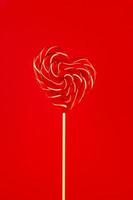 singolo san valentino giorno a forma di cuore lecca-lecca su rosso sfondo. foto