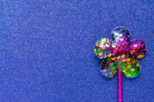 Magia bastone a partire dal paillettes nel fiore forma su blu luccichio sfondo. creativo piatto posare vicino su foto