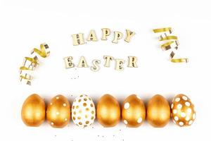 Pasqua festivo decorazione. superiore Visualizza di Pasqua uova colorato con d'oro dipingere e iscrizione nel inglese contento Pasqua. di legno lettere su bianca sfondo. vario tratteggiata design foto