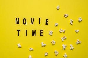 film tempo testo lettering con sparpagliato salato Popcorn su giallo sfondo. foto