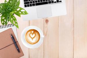 spazio di lavoro moderno con tablet laptop, notebook e tazza di caffè copia spazio su sfondo tavolo in legno. vista dall'alto. stile piatto. foto