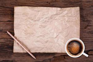 vecchio vuoto carta e un' tazza di caffè su di legno foto