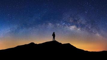 panorama paesaggio con latteo modo, notte cielo con stelle e silhouette di un' in piedi uomo su alto montagna. foto