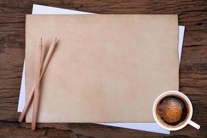 carta bianca con la matita e una tazza di caffè su legno foto