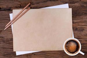 vecchio vuoto carta e un' tazza di caffè su di legno foto