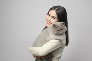 un' giovane donna è Tenere bello gatto , giocando con gatto nel studio su bianca sfondo foto