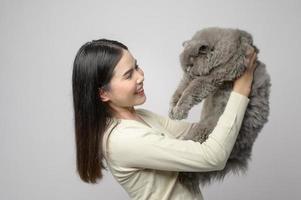 un' giovane donna è Tenere bello gatto , giocando con gatto nel studio su bianca sfondo foto