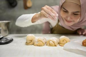 giovane bellissimo musulmano donna è cottura al forno nel sua cucina , forno e caffè negozio attività commerciale foto