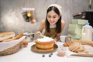 la giovane bella donna sta cuocendo nella sua attività di cucina, panetteria e caffetteria foto