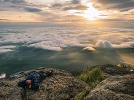 trekker posare giù su il scogliera con bellissimo Alba e mare di nebbia nel il mattina su khao luang montagna nel ramkhamhaeng nazionale parco, sukhothai Provincia Tailandia foto