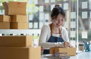 asiatico femmina imprenditori e in linea i saldi. donna è lavoratore autonomo, Lavorando a casa con un' piccolo attività commerciale proprietario. confezione consegna e pmi in linea marketing foto