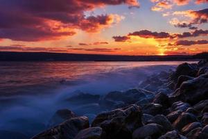prendere il sole lungo esposizione tramonto al di sopra di il mare con un' roccioso spiaggia. foto