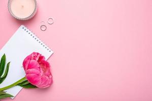 bellissimo rosa peonia fiore e taccuino con copia spazio per il tuo testo su pastello rosa sfondo foto