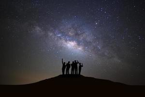 paesaggio con latteo modo galassia, stellato notte cielo con stelle e silhouette di persone in piedi contento uomo su alto montagna. foto