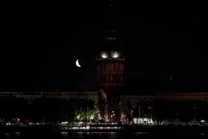 bellissimo trimestre Luna al di sopra di riga vecchio cittadina dietro a cupole Cattedrale orologio. foto