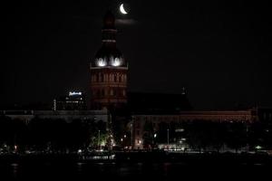 bellissimo trimestre Luna al di sopra di riga vecchio cittadina dietro a cupole Cattedrale orologio. foto