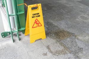 cartello giallo sdrucciolevole per pavimento bagnato sul terreno bagnato foto