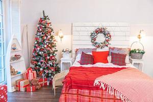 classico interno camera con Natale albero e tradizionale bianca rosso decorazioni. moderno pulito bianca classico stile interno design appartamento Camera da letto. Natale vigilia a casa. minimalista casa design. foto