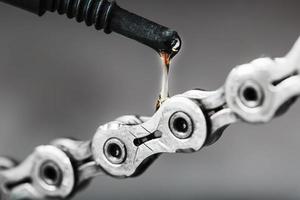 lubrificante un' bicicletta catena con un' far cadere di olio avvicinamento su un isolato grigio sfondo foto
