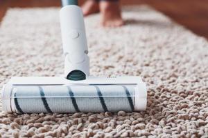 bianca ugello spazzola cordless vuoto addetto alle pulizie su il tappeto. il concetto di pulizia il premesse foto