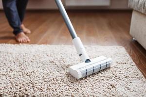 un' bianca turbo spazzola di un' cordless vuoto addetto alle pulizie su il tappeto. interno pulizia concetto foto