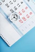 tempo su un' bianca allarme orologio dire bugie su il calendario e un' blu sfondo. foto