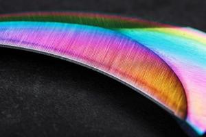 il curvo acuto lama di il kerambit pugnale è un' pendenza arcobaleno colore su un' buio sfondo. foto