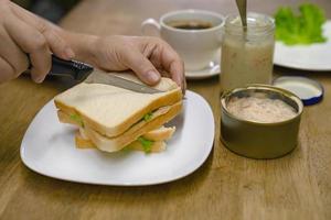 femmina taglio un' Sandwich per prima colazione con tonno Maionese foto