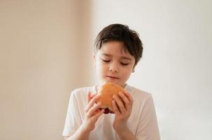 salutare ragazzo mangiare fatti in casa Bacon panini con misto la verdura, isolato ritratto contento giovane ragazzo avendo prima colazione a casa prima partire per scuola foto