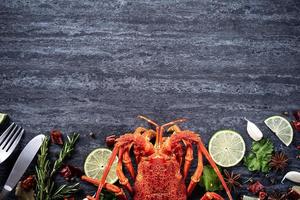 cucinato bollito aragosta, delizioso cena frutti di mare pasto impostato con coltello e forchetta su nero pietra ardesia sfondo, ristorante menù disegno, superiore Visualizza, alto foto