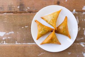 Samosa su bianca piatto su rustico piano.legno Visualizza. foto