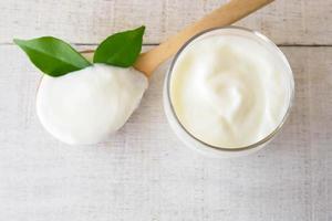 Yogurt tazza e cucchiaio su bianca legna sfondo. foto