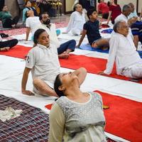 nuova delhi, india, 19 giugno 2022 -sessione di esercizi di yoga di gruppo per persone di diverse età nel tempio di balaji, vivek vihar, giornata internazionale di yoga, grande gruppo di adulti che frequentano lezioni di yoga nel tempio foto