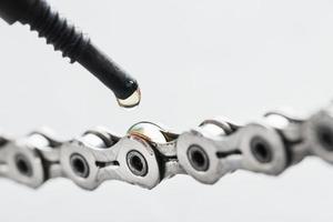 ingrassaggio un' bicicletta catena con un' far cadere di d'oro olio avvicinamento su un' grigio sfondo foto