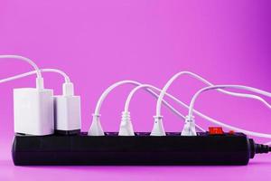 elettrico alimentazione filtro con inserito bianca spine di elettrico elettrodomestici su un' rosa sfondo. foto