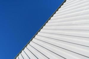 geometria di un' bianca ondulato metallo edificio contro un' blu cielo. foto