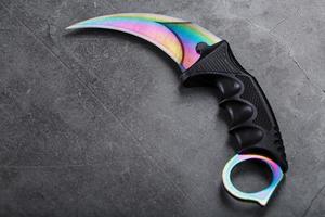 kerambit pugnale con un' color arcobaleno lama su un' buio strutturato sfondo. foto