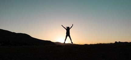 ragazza che salta al tramonto in montagna foto