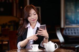 bella ragazza asiatica che utilizza Smart Phone in un caffè foto