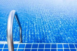 afferrare barre inossidabile nel il blu nuoto piscina foto