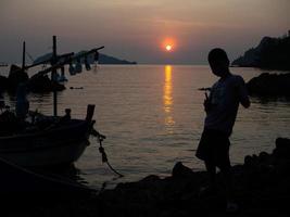 un peschereccio fermo sulla costa al tramonto foto