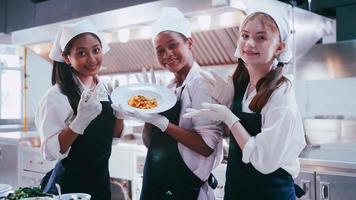 gruppo di studentesse avendo divertimento apprendimento per cucinare. femmina studenti nel un' cucinando classe. foto