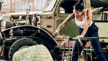 attraente giovane donna meccanico lavoratore riparazione un' Vintage ▾ auto nel vecchio box auto.