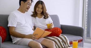 contento asiatico coppia lettura libro insieme nel un' vivente camera. foto