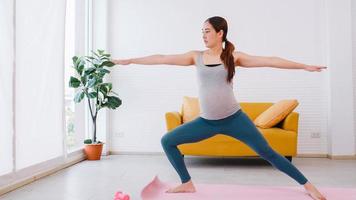 bellissimo giovane asiatico incinta donna nel abbigliamento sportivo è fare yoga a casa. foto
