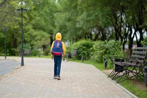 ragazzo con una felpa gialla con uno zaino sulla schiena che va a scuola. concetto di ritorno a scuola foto