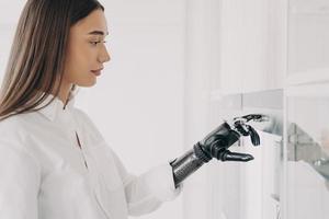 la donna europea disabile sta cucinando. la mano informatica robotica sta accendendo il forno in cucina. foto