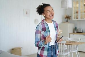 la ragazza felice eccitata in airpods sta tenendo il telefono cellulare. l'adolescente canta nella mattina del fine settimana. foto